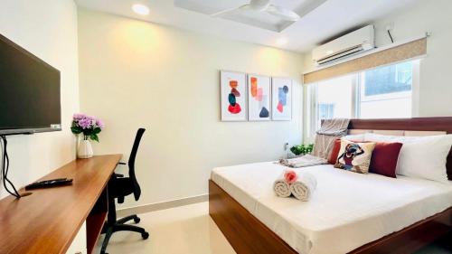 a bedroom with a bed with a desk and a computer at Olive Service Apartments Gachibowli in Hyderabad