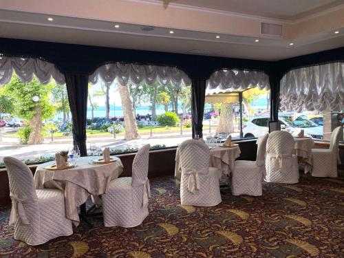 a restaurant with white tables and chairs and a window at Hotel Columbus sul Lago in Bolsena
