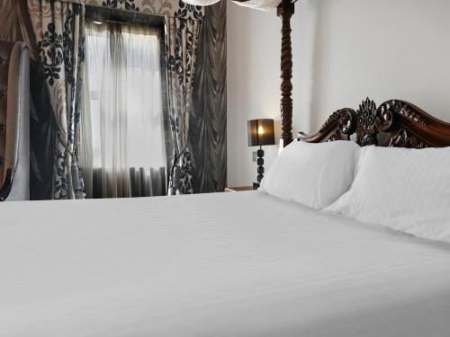 a bed with white sheets and pillows in a bedroom at Dryfesdale Hotel - BW Signature Collection in Lockerbie