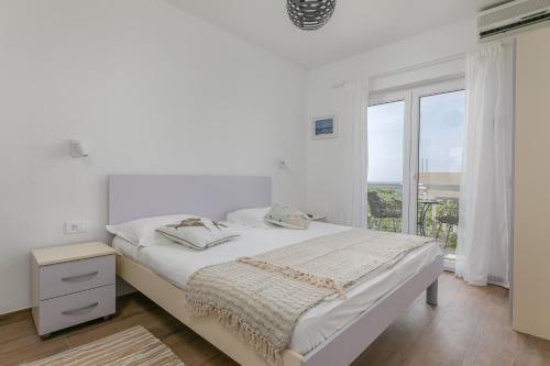 a white bedroom with a bed and a window at La casa di Nonno in Milna