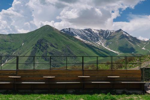 a wooden bench with mountains in the background at Gudauri Lodge in Gudauri