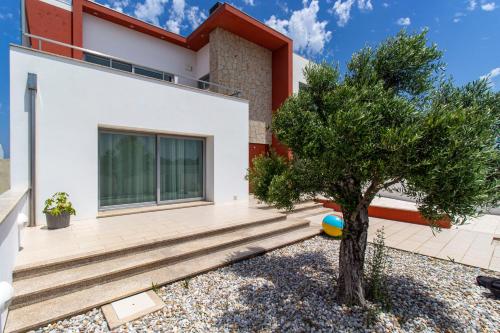 una casa con un árbol delante de ella en O Cantinho Entre a Ria e o Mar, en Torreira