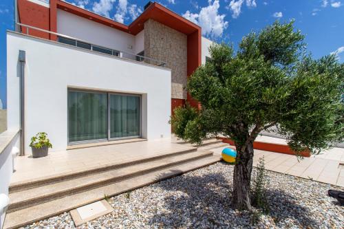 a house with a tree in front of it at O CANTINHO ENTRE A RIA E O MAR - with hot water pool all year round in Torreira