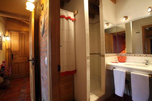 y baño con lavabo, espejo y toallas. en Casa rural El Leñador en Ávila