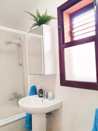 a white bathroom with a sink and a window at Allamanda Home in Caleta De Fuste