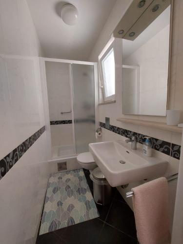 a white bathroom with a sink and a toilet at Rooms Diana in Dubrovnik