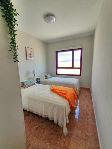 a bedroom with two beds and a window at Allamanda Home in Caleta De Fuste
