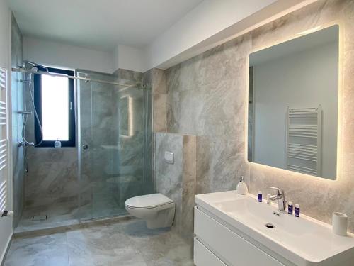 a bathroom with a shower and a toilet and a sink at Ada Luxury Apartments 57 in Mamaia