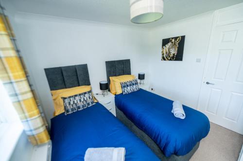 two beds in a room with blue sheets at Beautiful Abode, Fast Wifi, Parking, Frenchay in Bristol