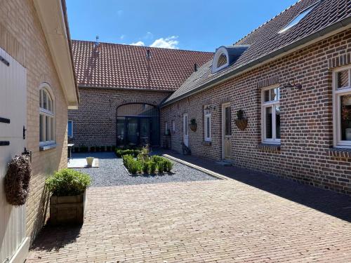 B&B Aasterbergerhoeve في Echt: مبنى من الطوب مع ساحة مع نباتات الفخار