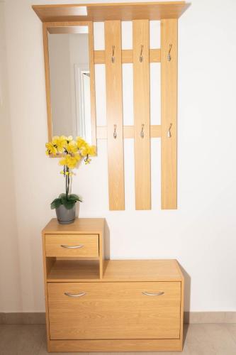 a wooden dresser with a vase of yellow flowers on it at Apartment Marta in Raša