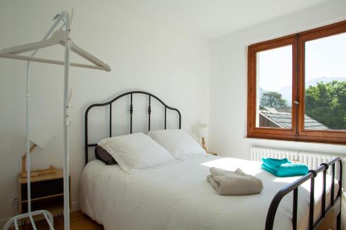 a bedroom with a large white bed with a window at Maison proche lac, vélos, parking in Sévrier