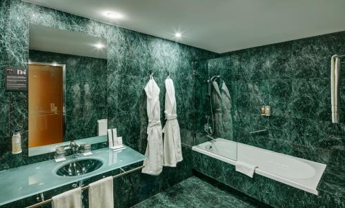 a bathroom with a sink and a tub and a mirror at Sercotel AB Rivas in Rivas-Vaciamadrid