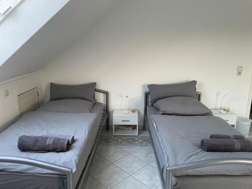 two beds sitting next to each other in a room at Parkplätze, Einzelbetten, 2 Balkone, fast Wi-Fi 100 Mbit, Homeoffice, Aufzug, lichtdurchflutet, Panoramablick in Erlensee