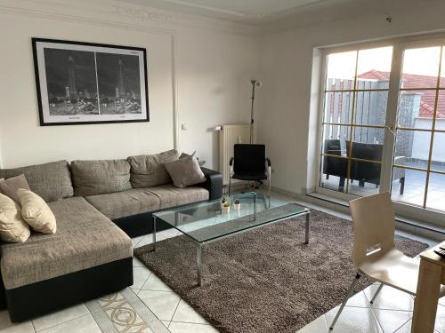 a living room with a couch and a glass table at Parkplätze, Einzelbetten, 2 Balkone, fast Wi-Fi 100 Mbit, Homeoffice, Aufzug, lichtdurchflutet, Panoramablick in Erlensee