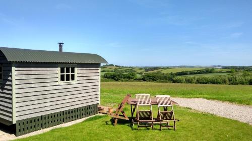 a table and chairs next to a small building at Shepherd's Lodge - Shepherd's Hut with Devon Views for up to Two People and One Dog in Wrangaton