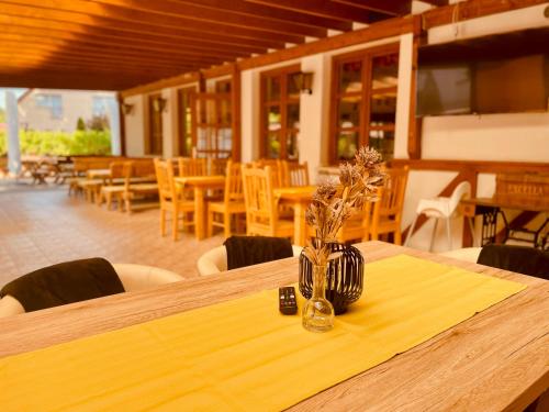 una mesa de madera con un jarrón con flores. en Sommer Panzió en Balatonföldvár