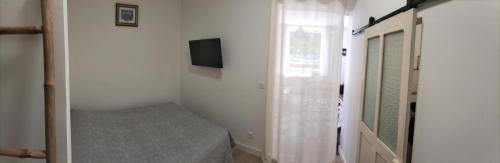 1 dormitorio con 1 cama, TV y espejo en Joli logement centre ville avec clim, en Orange