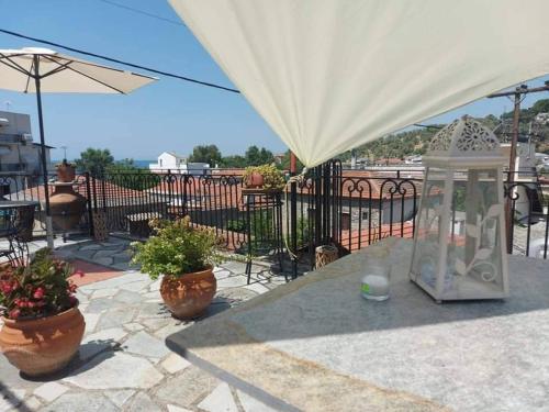 a patio with two potted plants and an umbrella at Το Πέτρινο Αρχοντικό in Afissos