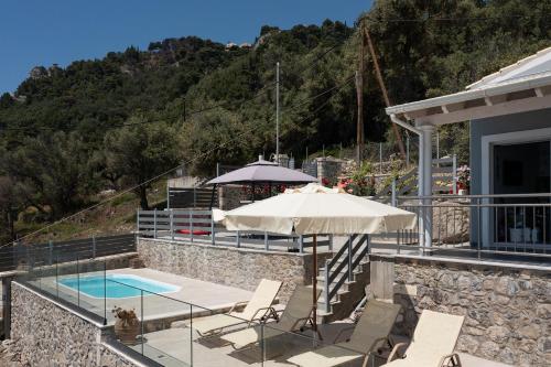 un patio con mesa, sombrilla y piscina en Villa Renata & Villa Filippos with private Plunge Pool by Konnect, en Agios Gordios