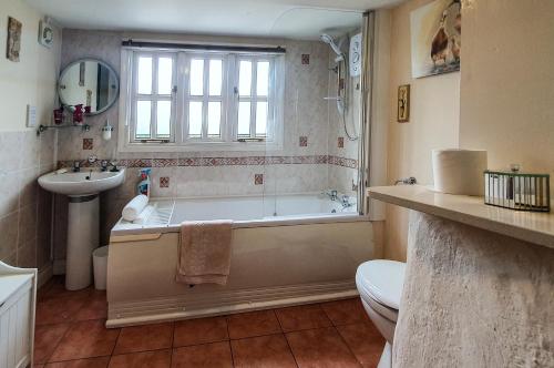 uma casa de banho com uma banheira, um WC e um lavatório. em Magnolia Cottage em Wellington