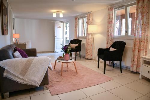 uma sala de estar com um sofá, cadeiras e uma mesa em Le Hameau d'Eguisheim - Chambres d'hôtes & Gîtes em Eguisheim
