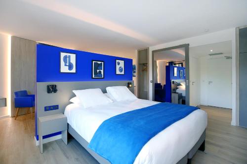 a bedroom with a large bed with blue walls at Logis Hôtel & Spa Déjeunez Sous L'Arbre in Rousset