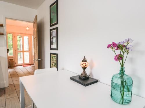 a white table with a vase of flowers on it at Swaledale Watch House Annexe in Wigton