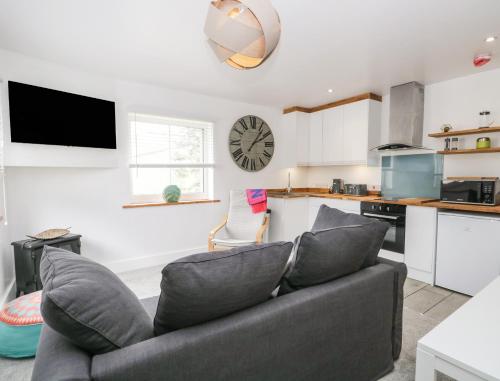 a living room with a couch and a clock on the wall at Swaledale Watch House Annexe in Wigton