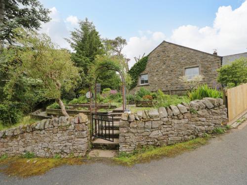a stone house with a gate and a stone wall at Swaledale Watch House Annexe in Wigton