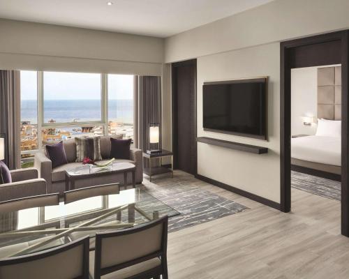 a living room with a bed and a television at Hyatt Regency Al Kout Mall in Kuwait