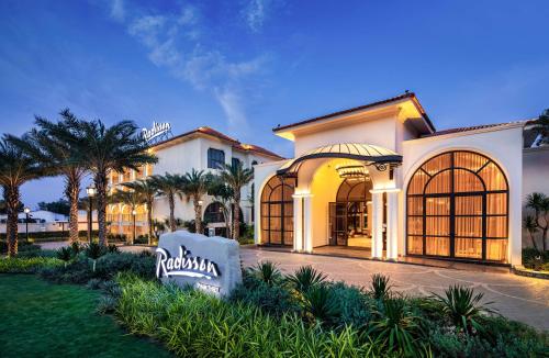 a large white house with palm trees in front of it at Radisson Resort Phan Thiet in Phan Thiet