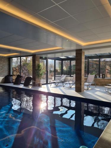 a pool in a hotel lobby with chairs and tables at Maison Jenny Hotel Restaurant & Spa in Hagenthal-le-Bas