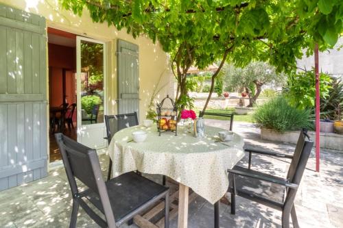 une table et des chaises sous un arbre sur une terrasse dans l'établissement Maison du Grichet - Piscine privée, à Condom