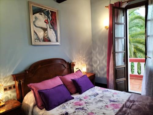 a bedroom with a bed with purple pillows and a window at Villa Burión in Llanera