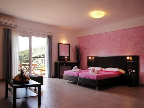 - une chambre avec un lit et un mur rose dans l'établissement Dafni studios no2, à Parga