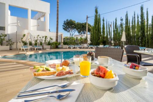 a table with a breakfast of fruit and juice next to a pool at INNER Hotel Rupit "Adults Only" in Cala d´Or