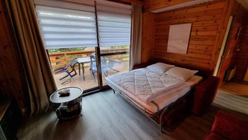 a bedroom with a bed and a balcony with a table at Séjour cosy au Chamily in Somme-Leuze