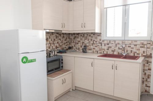 a kitchen with white cabinets and a white refrigerator at Timbaki'Theodosia'T Brothers in Tympáki