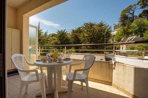 une table et des chaises sur un balcon avec vue dans l'établissement Les Petits Marins - A 150m de la plage, à Saint-Cast-le-Guildo