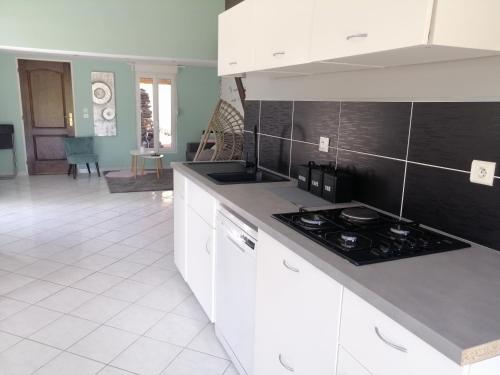 une cuisine avec des armoires blanches et un four à plaques de cuisson dans l'établissement Le temps d'une pause dans l'Yonne, à Charmoy