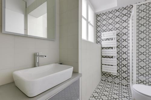 uma casa de banho branca com um lavatório e um espelho em AC 4 people apartment Louvres Place Vendome Paris center by Weekome em Paris