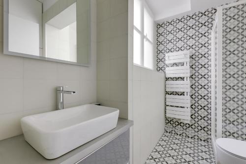 une salle de bain blanche avec un lavabo et un miroir dans l'établissement AC 4p apt - Louvres Place Vendome Paris center by Weekome, à Paris