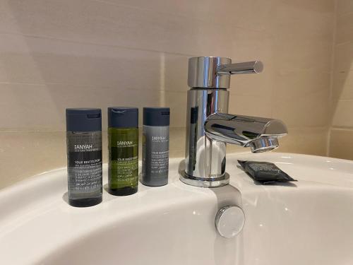 a bathroom sink with three bottles ofodorizers and a faucet at Silverdale Mews in Eastbourne