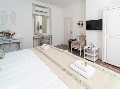 a white bedroom with a large bed and a chair at Villa Bella in Badacsonytomaj