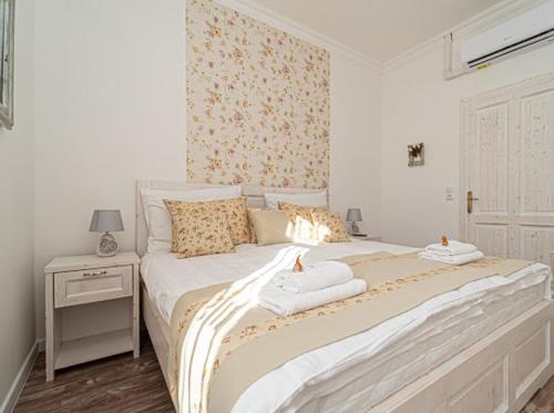 a white bedroom with a bed with towels on it at Villa Bella in Badacsonytomaj