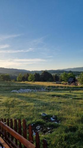 a wooden fence in a field with a creek at A Pine vikendica u srcu Zapadne Srbije in Nova Varoš