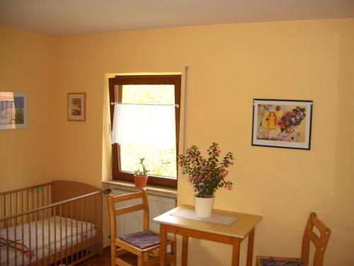 a room with a crib and a table and a window at Ferienwohnung am Busterbach in Seebach
