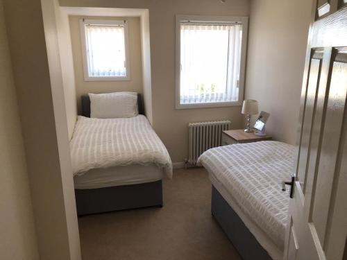 a small bedroom with two beds and two windows at Beautiful 3-Bed Apartment in Gourock in Gourock