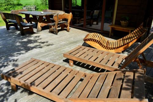 a group of wooden benches and a table on a deck at Kaimukas - namelis prie ežero keturiems in Dvarčėnai